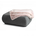 havaneser.shop Wohndecke aus weichem Webpelz in zartem Rosa, elegant drapiert auf einem grauen Polsterhocker.