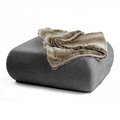 havaneser.shop Wohndecke aus Webpelz in Beige und Braun, gefaltet auf einem grauen Polsterhocker